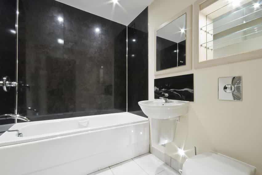 Bathroom with large black granite wall tilework and smaller ceramic flooring tiles in white