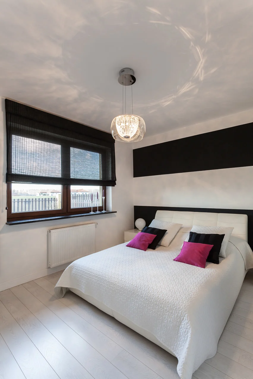 Room with magenta pillows, window and leather headboard