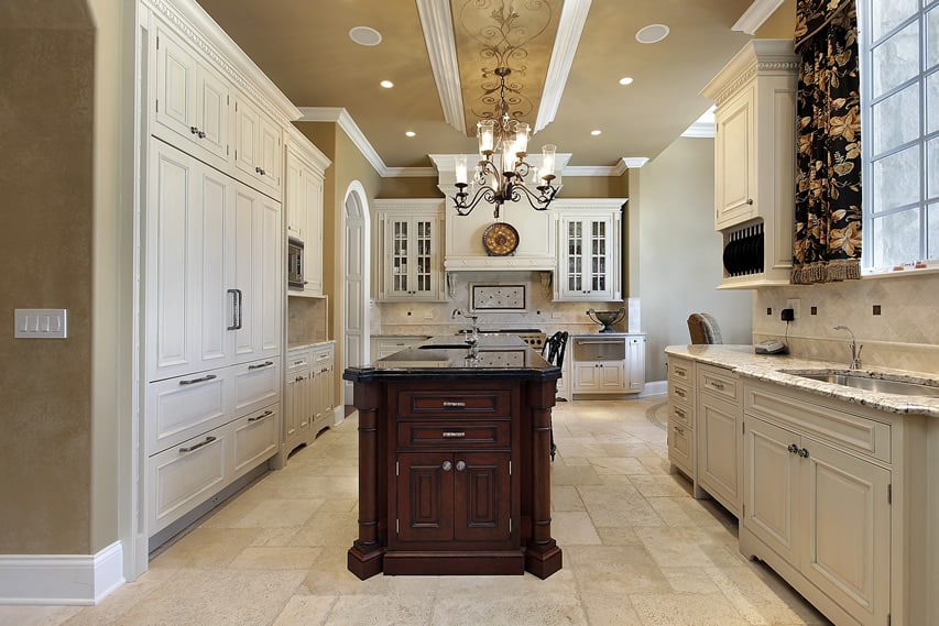 Elegant traditional kitchen in luxury home with white cabinets, dark cabinet island and double sinks
