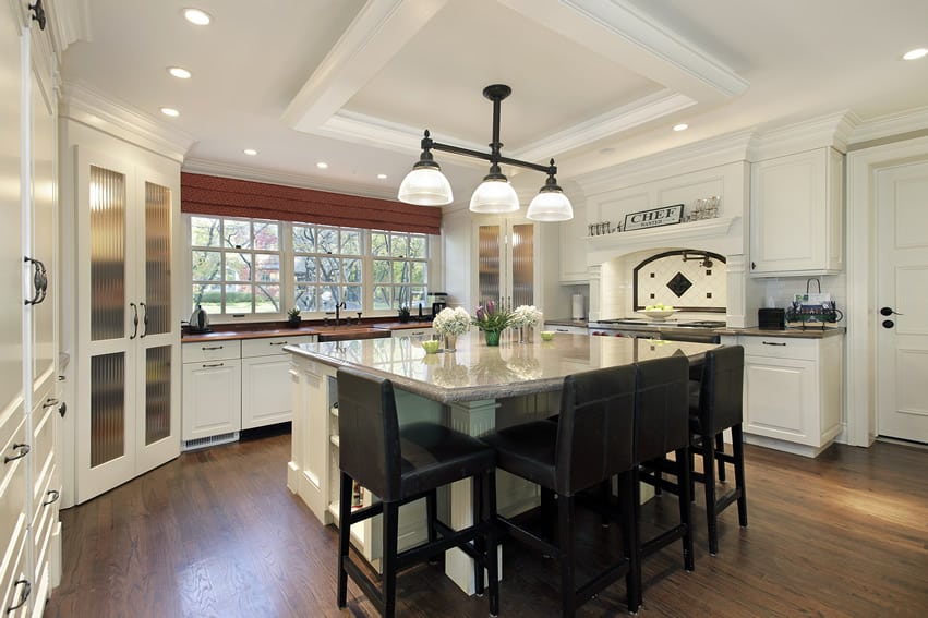Kitchen with white cabinets, light beige granite countertops, island and eat-in area for dining