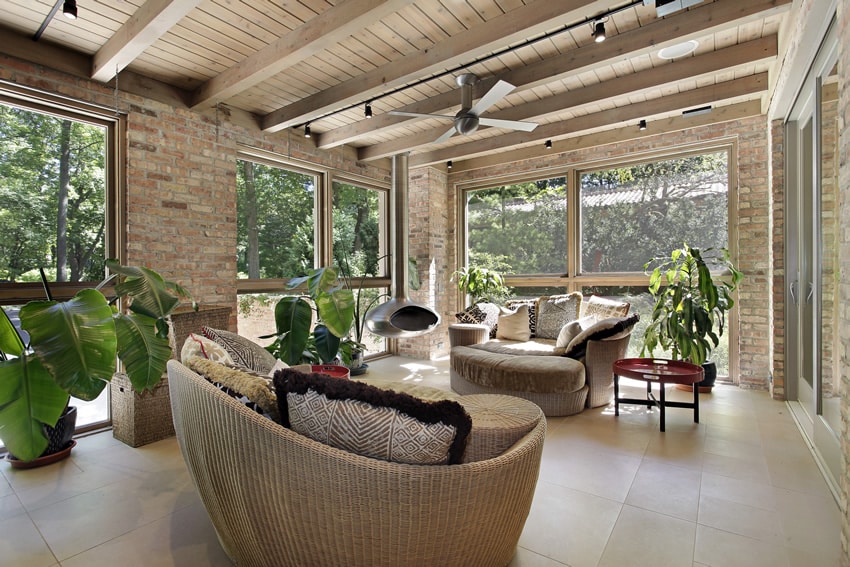 Brick sunroom with wicker furniture and wood plank ceiling