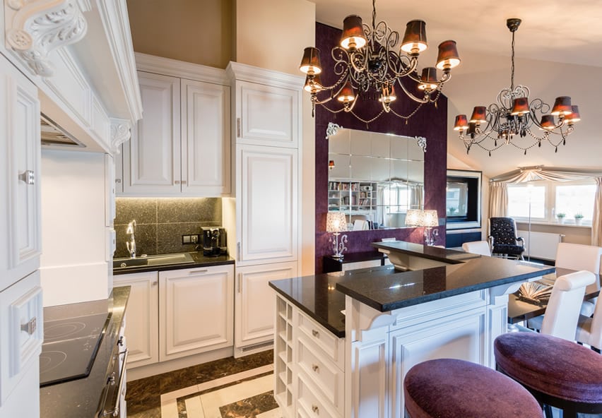 Raised dining area and white paneled kitchen cabinets with French chandeliers