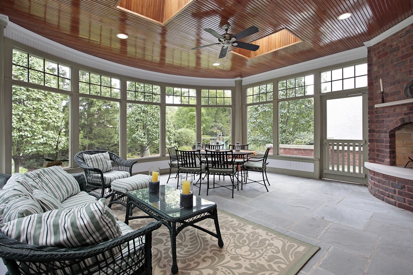 Rounded sunroom with brick fireplace and wood ceiling with skylights