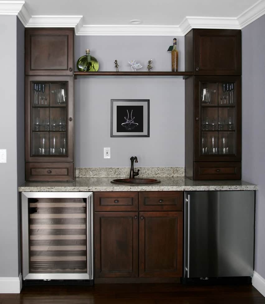 Wet bar in home with fridge, sink and cabinets