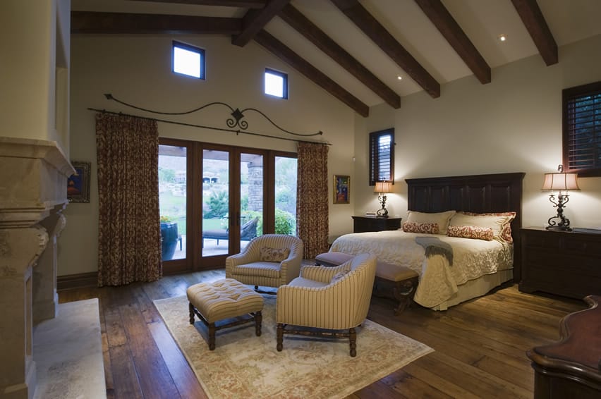 Bedroom with vaulted ceiling, exposed beams and large wood headboard