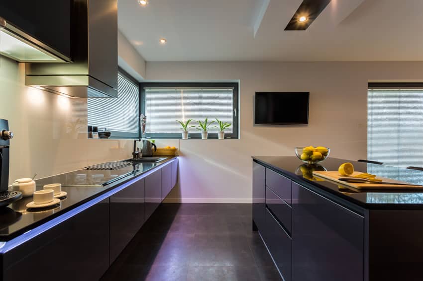 Kitchen with television on the wall, track lighting and windows with blinds