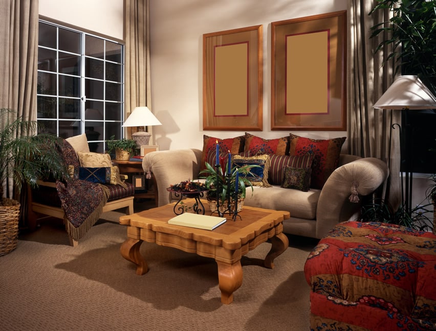 Room with taupe carpet, tabble with curvy legs and couch with red pillows