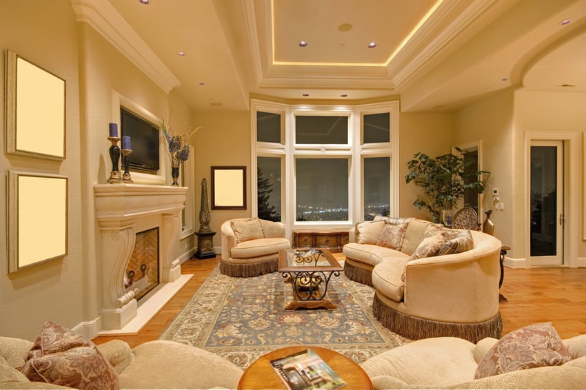 High end living room with large white fireplace and tray ceiling
