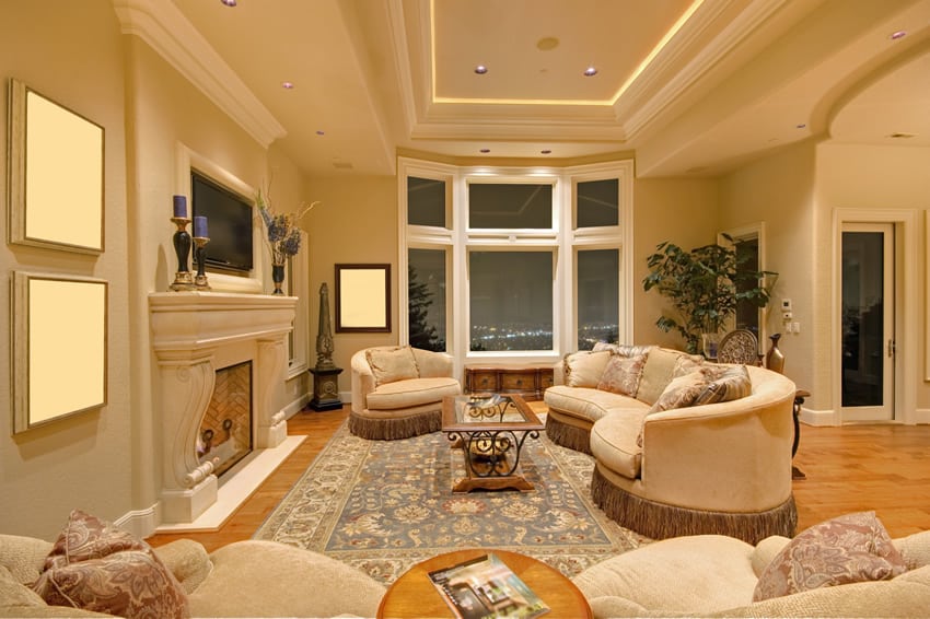 Room with round-edged sofa and fireplace with moldings