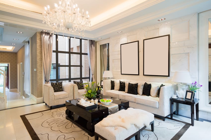 Elegant living room with tray ceiling, white couches, and chandelier