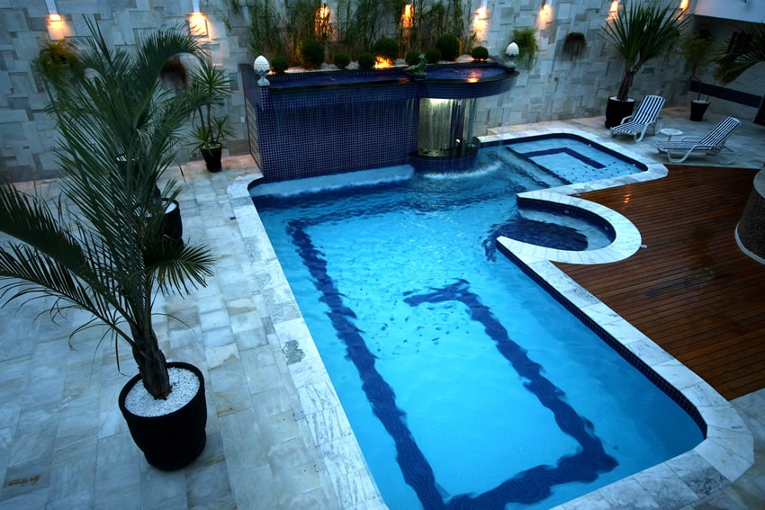Pool with mosaic tile spillway and wooden deck surround