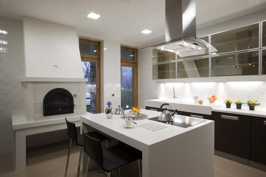 Modern kitchen with black cabinets, white counter and fireplace