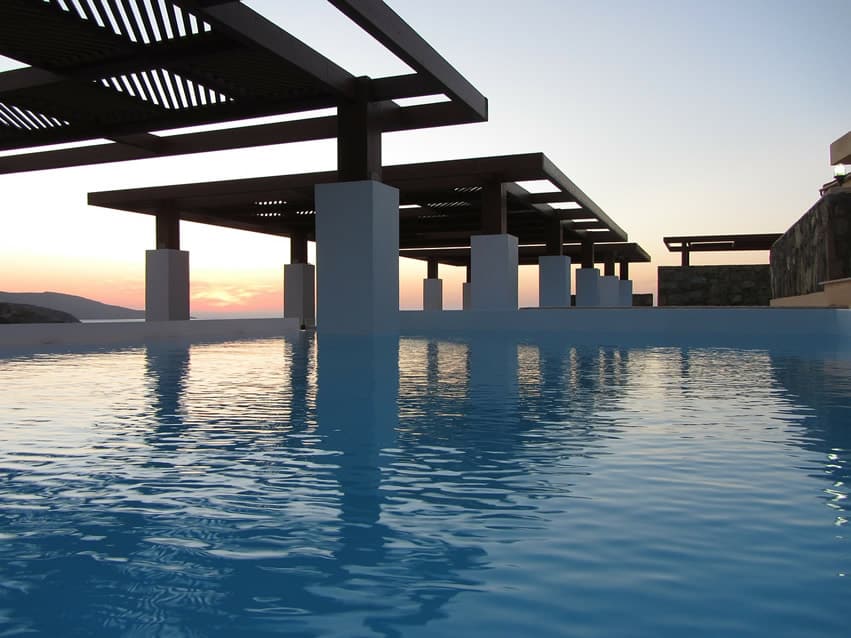 Modern swimming pool with white pillars overlooking ocean