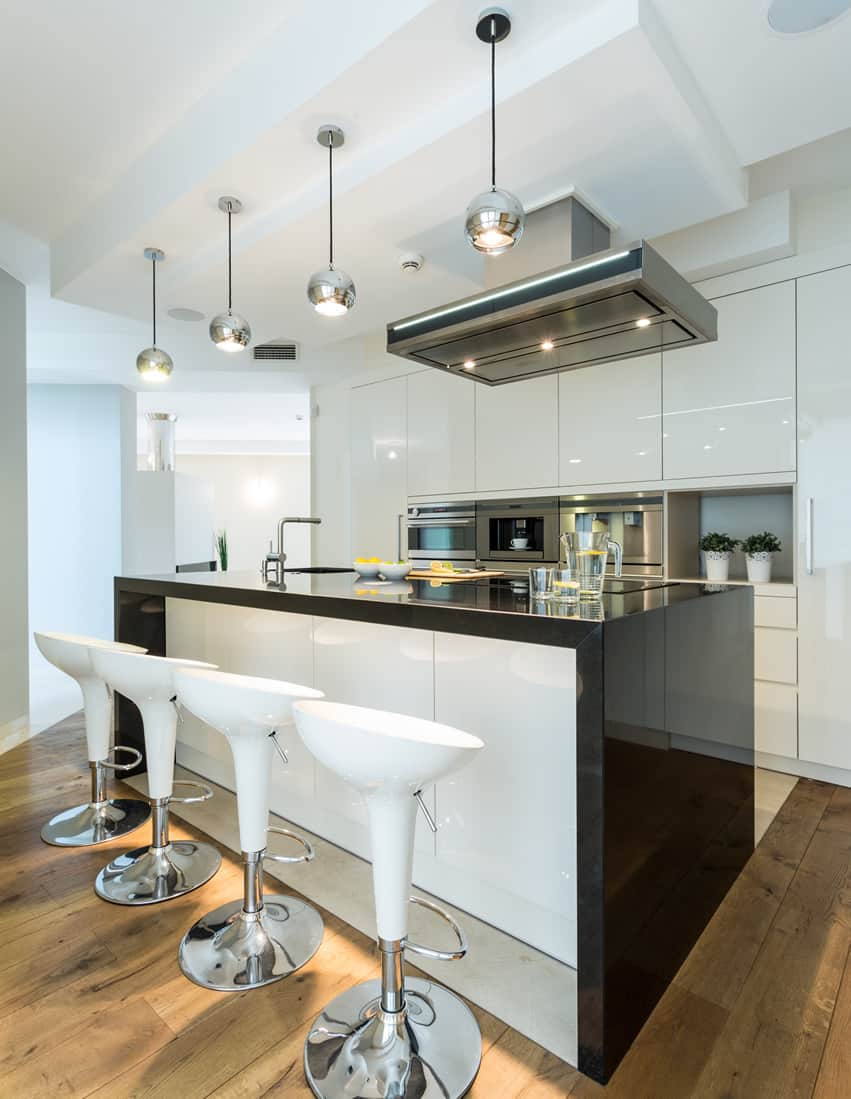 Kitchen with glossy white bar stools, stainless steel faucet and pine floors
