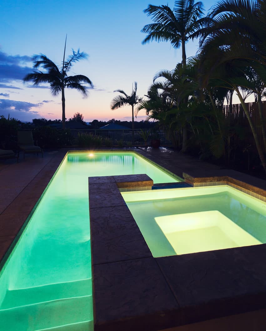 Rectangular swimming pool with hot tub and palm trees