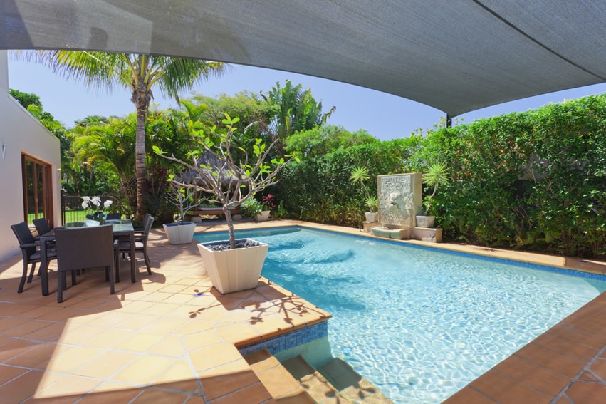 Pool with canopy covered patio and outdoor furniture in rattan finish