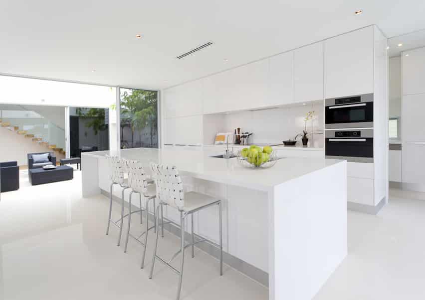All white kitchen with chairs with woven backrest and aluminum feet