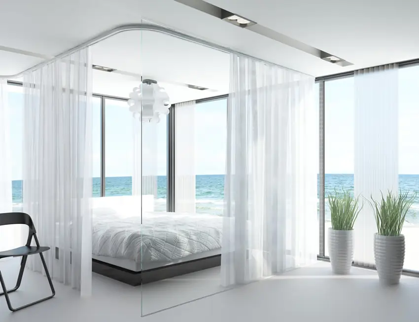 Bedroom with white theme, floor to ceiling bed curtains and picture windows