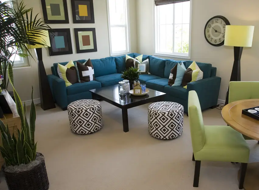 Room with blue green couch, patterned throw pillows and black center table