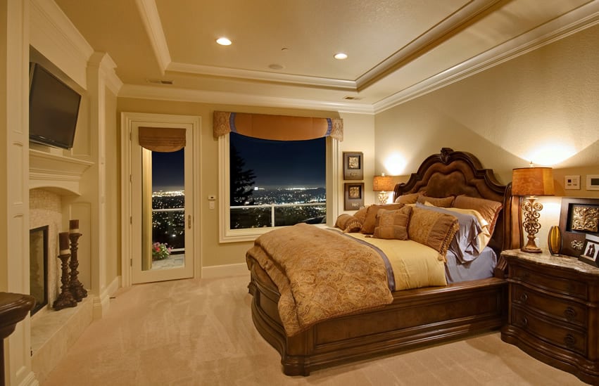 A suite size bedroom with tray ceiling and view of city lights