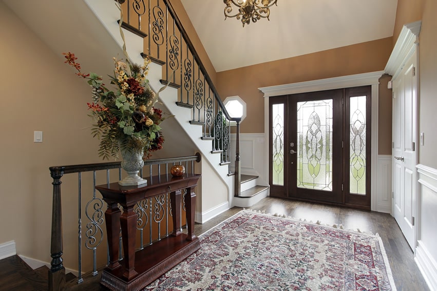 Decorative glass front door, dark oak floors and foyer rug