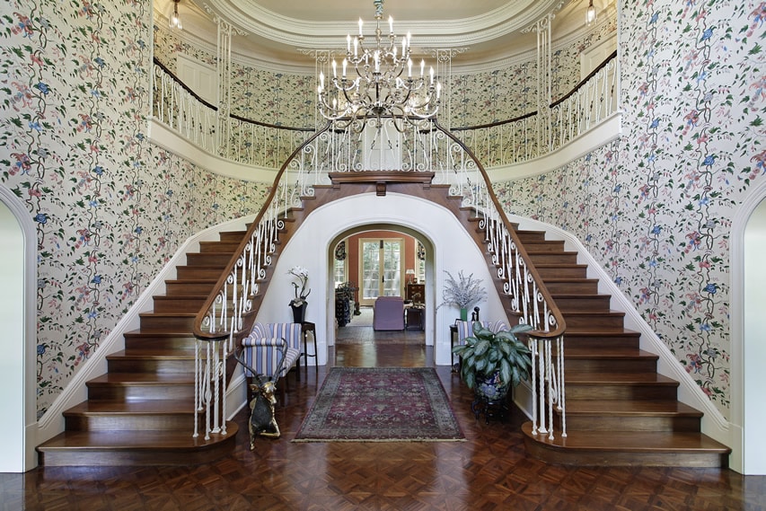 Grand dual staircase with floral wallpaper, plants and deer sculpture