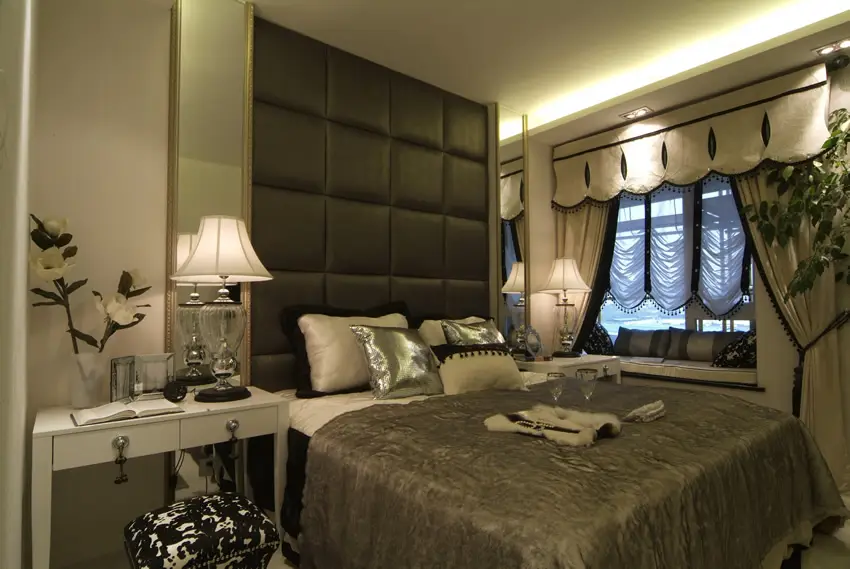 Room with fabric cushioned headboard, glass lamps and curtains with drapes