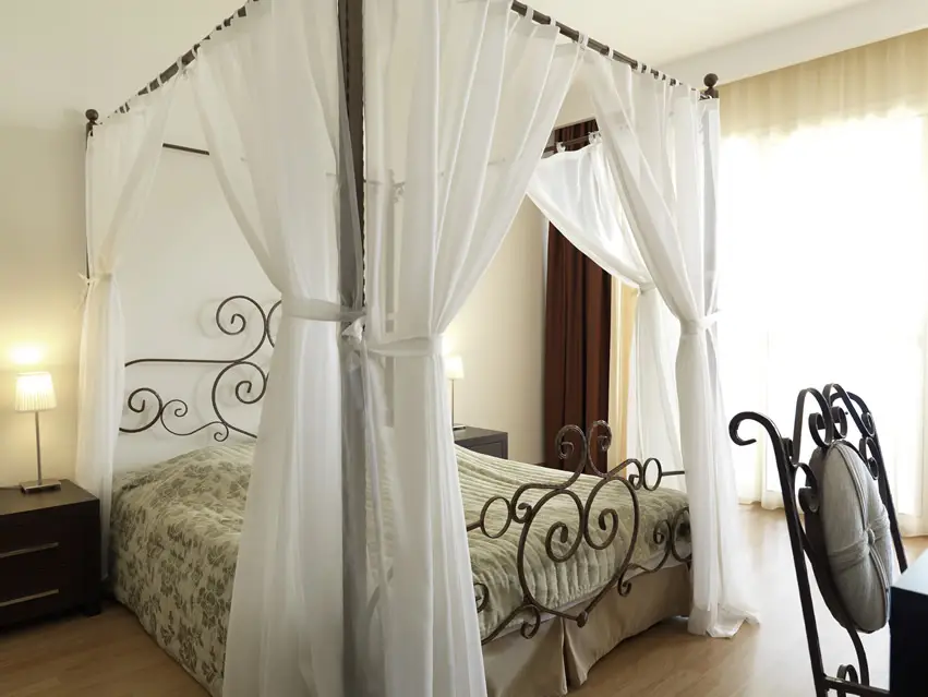 Four post bed with white curtains