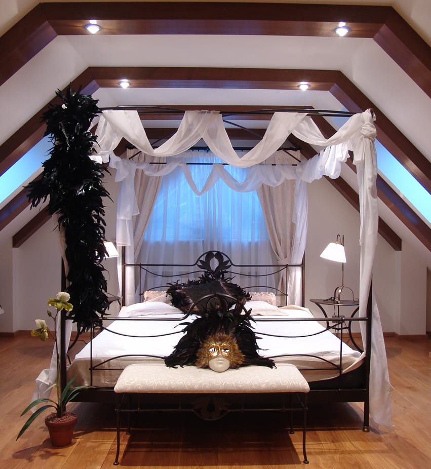 Impressive bedroom with four post bed exposed wood beam ceiling