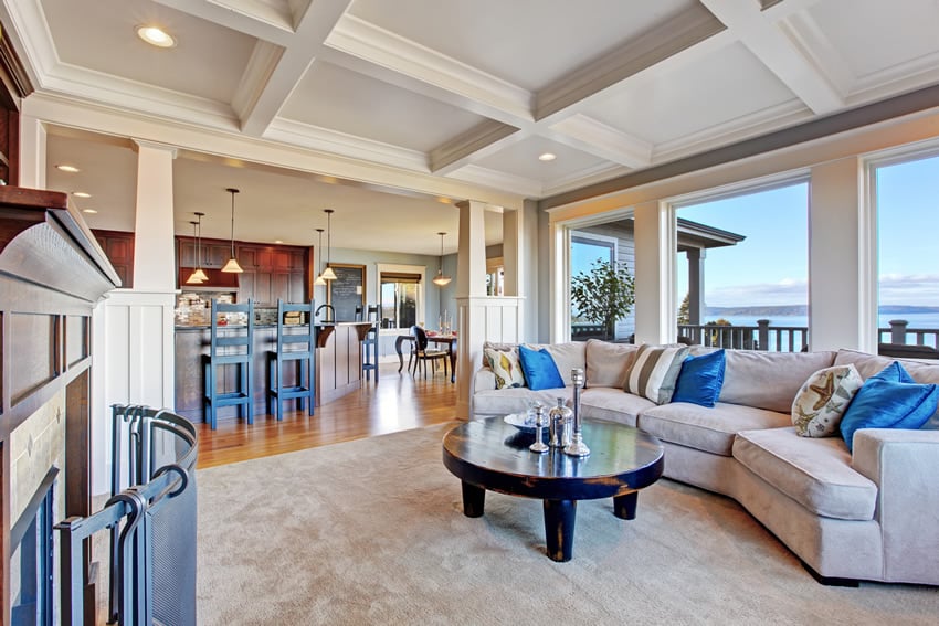 Room with carpet flooring, blue accent pillows and breakfast stools