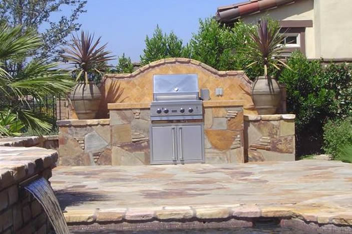 Kitchen made of natural stone with view of pool water feature