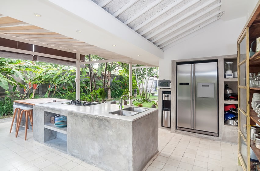 Outdoor kitchen with concrete counter and stainless steel fridge