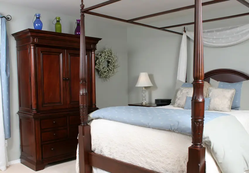 Wood stained wardrobe in bedroom with four post bed