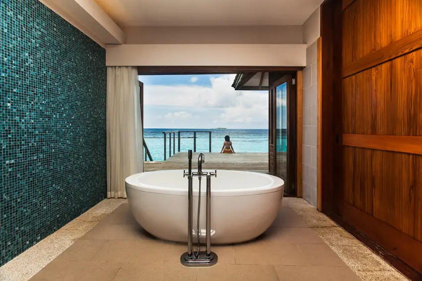 Round bathrub wuith mosaic tile wall on one side and wood planks on the other