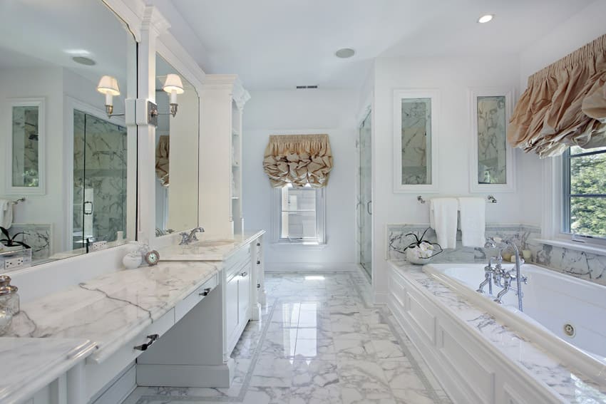 Bathroom with frilly curtains and Statuario marble on floors, tub and vanity