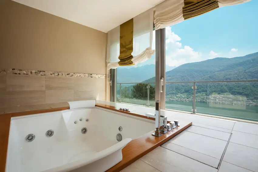 Recessed tub with mountain view and half-walled travertine tiles