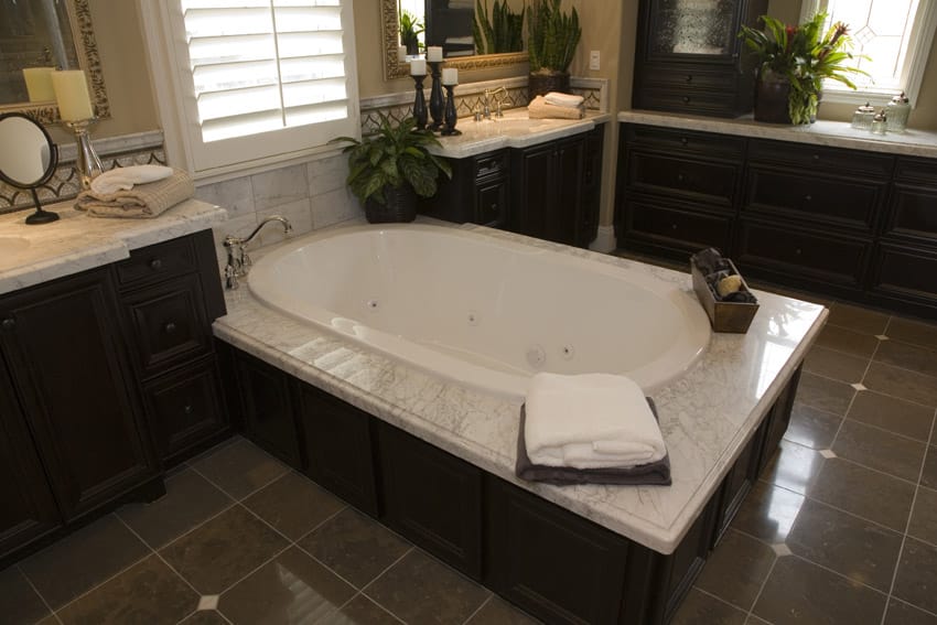Large jet tub in bathroom suite with dark cabinets