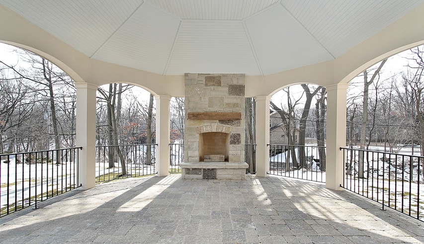 Large outdoor patio with fireplace and wrought iron railing