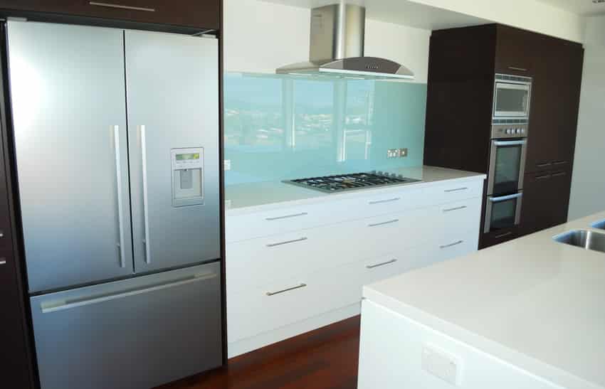 Light blue backsplash in modern kitchen with brown and white cabinets