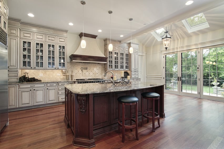 Luxury white kitchen with elegant glass faced cabinetry and wood flooring