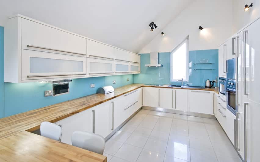 Modern kitchen with white cabinetry and solid blue back splash