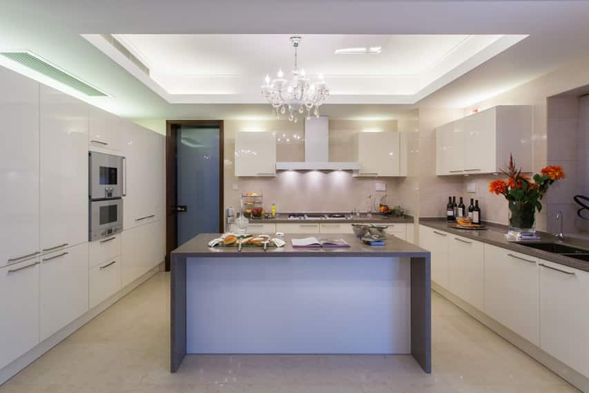 Modern white kitchen with grey counter and chandelier