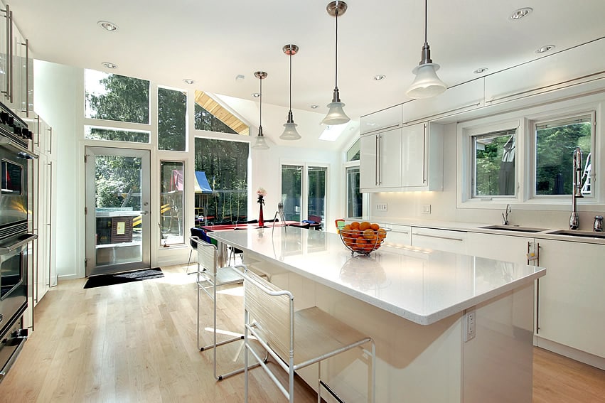 Open white kitchen design with wood flooring and glass door