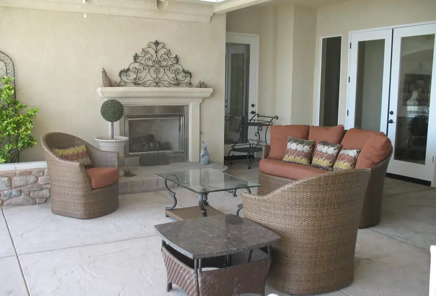 Fireplace with decorative metal piece, rattan furniture and glass table