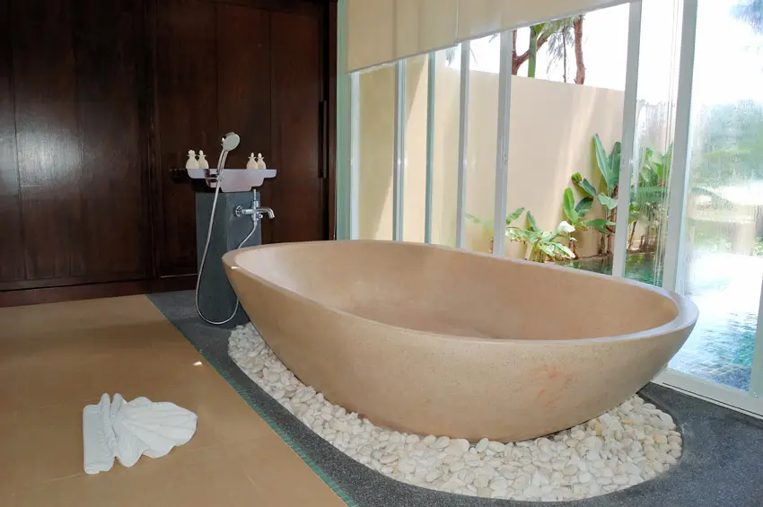 Quartz tub with white river stones and sliding door to the pool