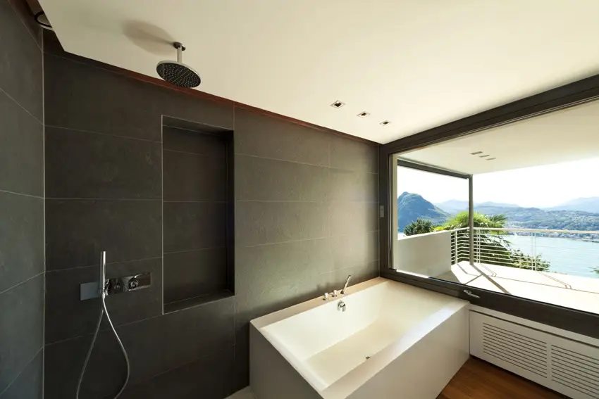 Partitionless bathroom with black wall tiles with square tub and shower