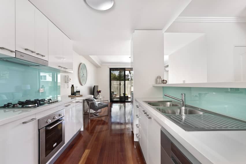 White galley style kitchen with modern aqua backsplash