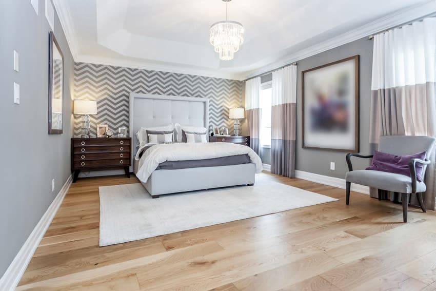 Bedroom with zig zag design wall, grey headboard and wood flooring
