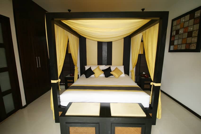 Black and yellow room with yellow draped curtains over bed