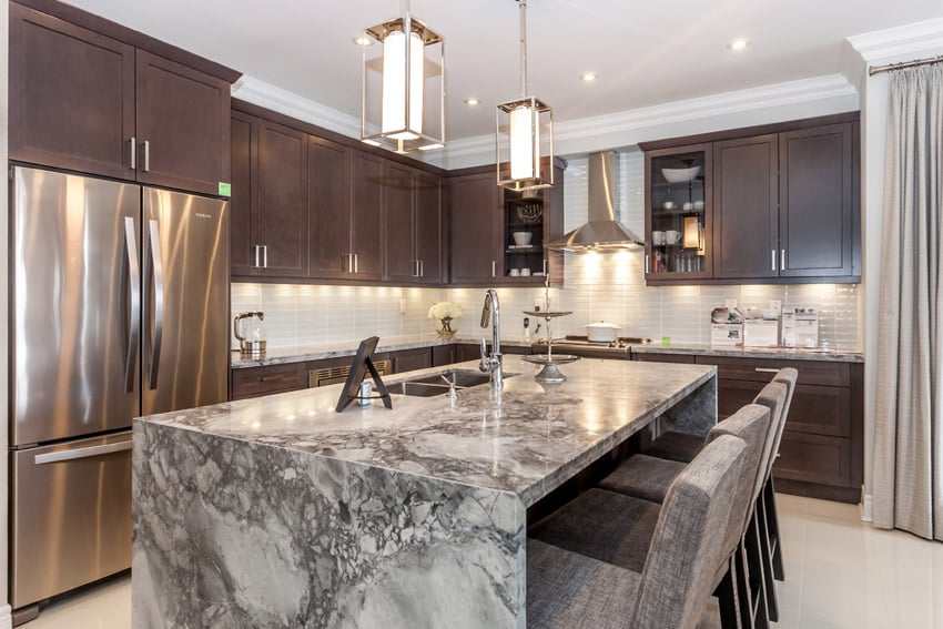 Kitchen with dark cabinets with chrome handles and subway tile backsplash